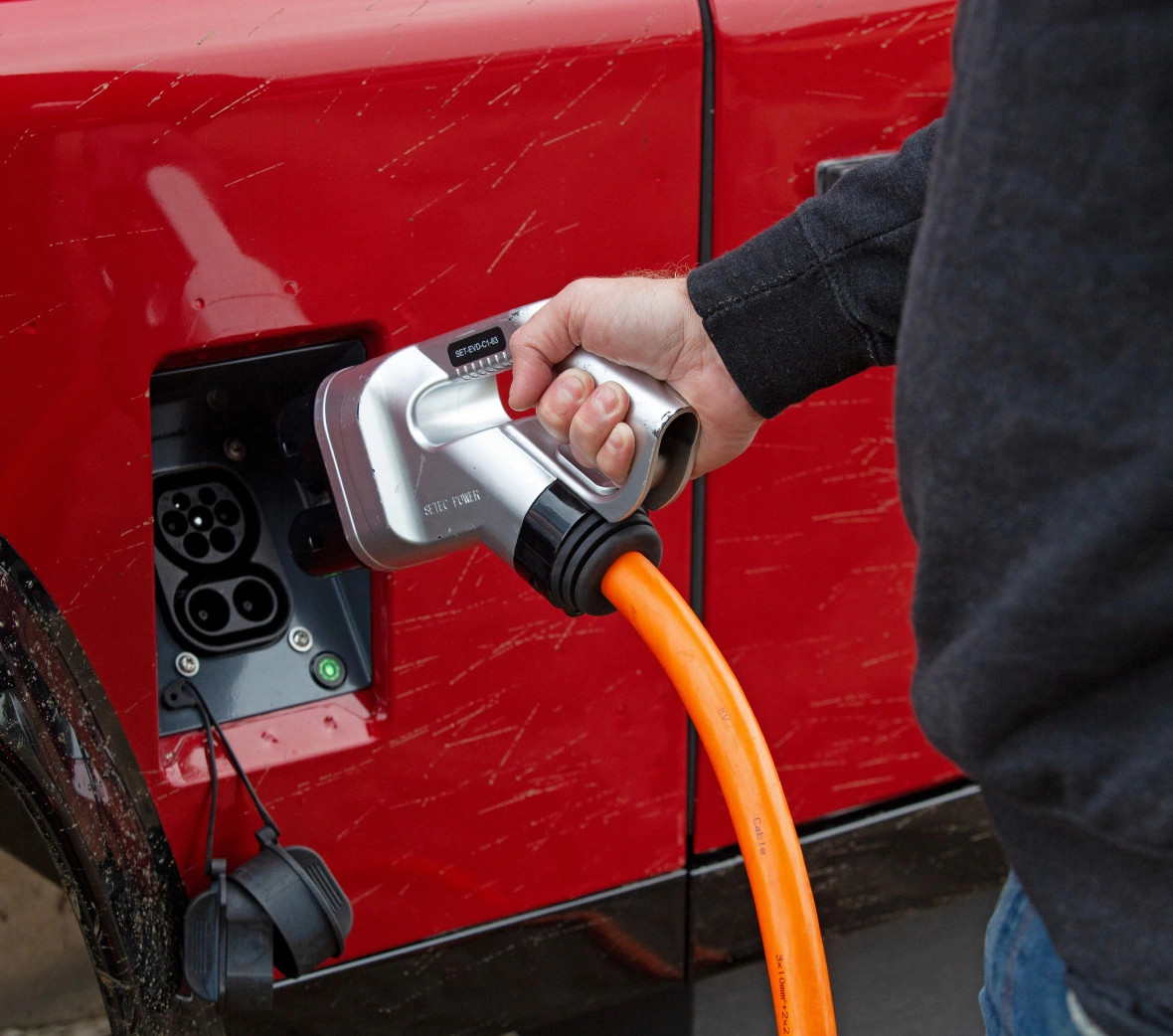 A wall-mounted Level 2 EV charging station plugged into an electric vehicle in a clean garage showing the 240V EVSE setup.